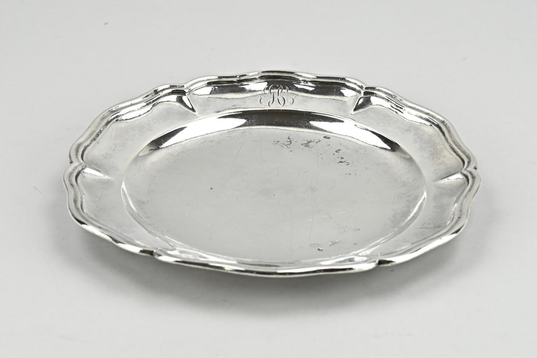 Silver plate, probably Dutch: Silver plate, 18th century, round model with a contoured edge and a double edge. ø23x2.5cm. approx. 391 grams. On the front is a monogram engraving. On the back is an engraving: GC Stamped with