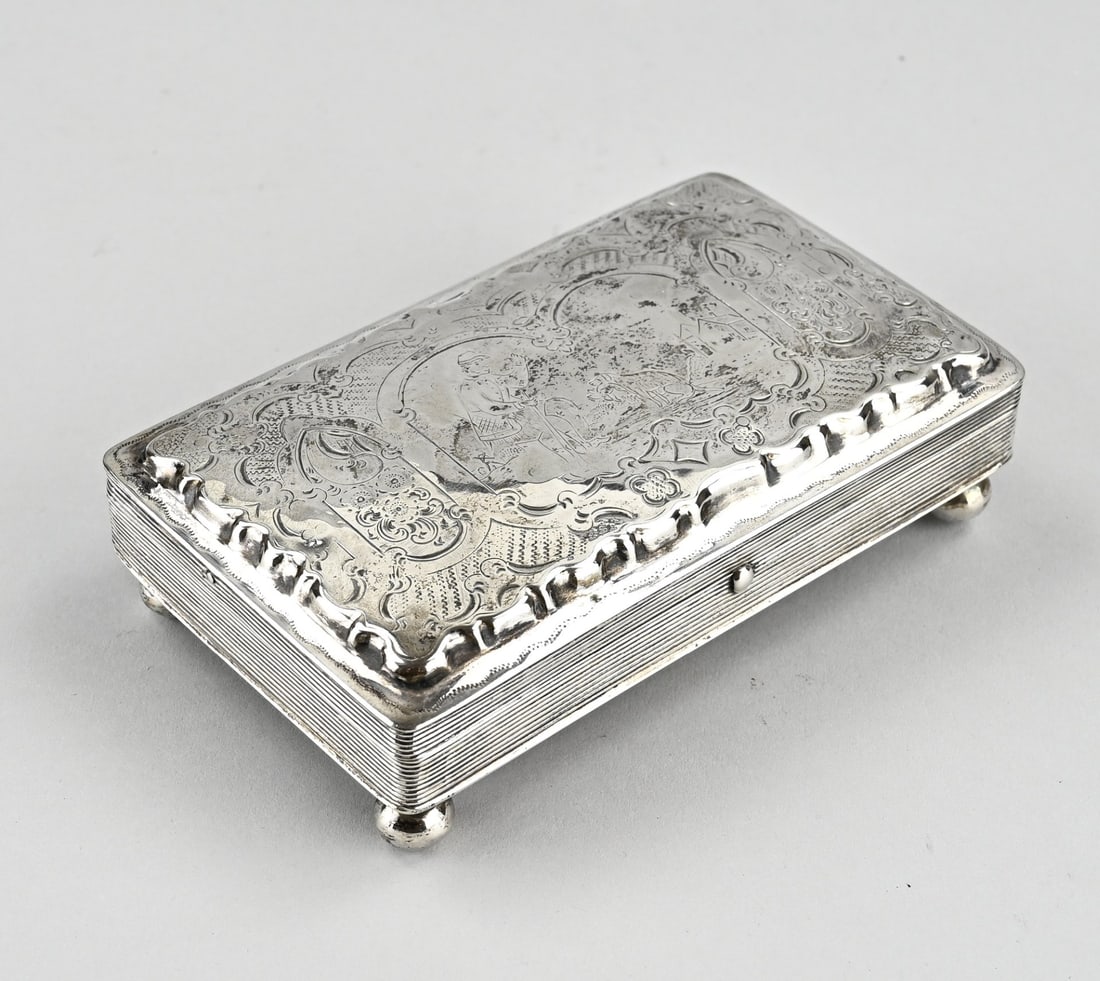 Silver box: Silver box, 833/000, rectangular model placed on 4 ball feet. The hinged lid is decorated with engraving featuring a representation of a man with a dog. 13x8.5x3.5cm. approx. 156 grams. MT.:DH Greup,
