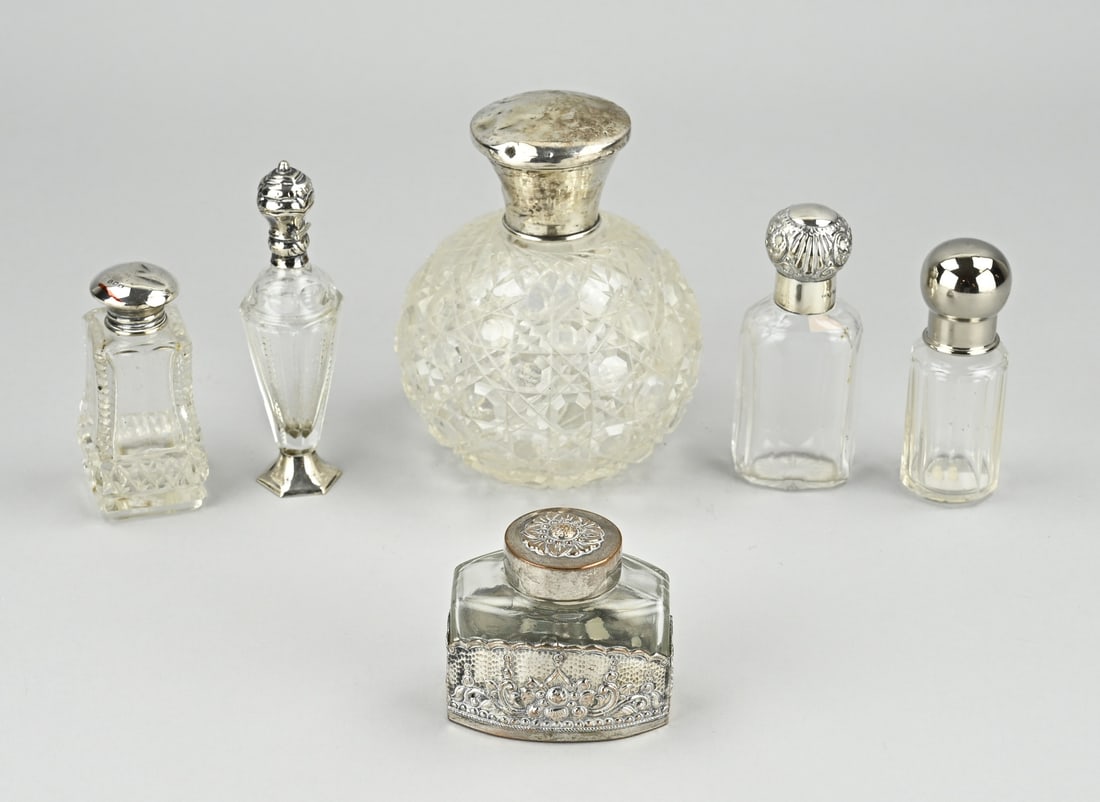 Lot silver/plated (6x): Lot with 6 (fragrance) bottles of which 5 with a silver cap, collar and foot. And a cylindrical bottle with a domed plated cap. Various contents. 6-12cm. Some slightly dented. In good condition.