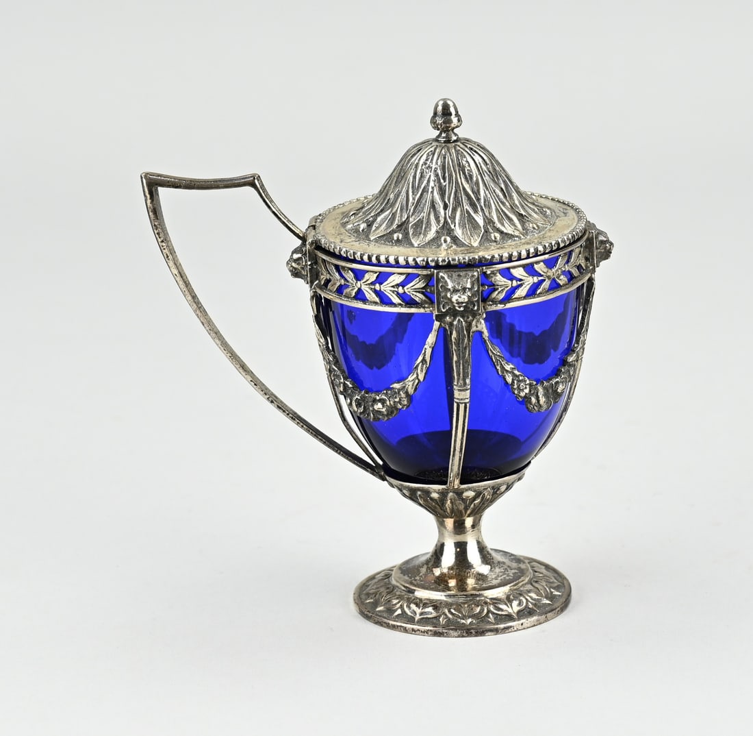 Silver mustard pot with blue glass: Silver mustard pot with blue glass, 833/000. Openwork silver holder decorated with garlands, lion heads and floral work. With hinged lid with leaf decoration. MT.: BWEldick, Zutphen. 1 garland
