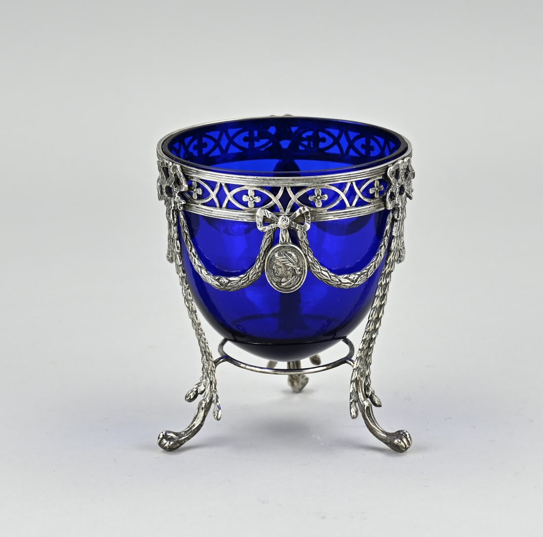Silver candy dish with blue glass: Sugar coupe with silver, 833/000, and blue glass bowl. Coupe with silver holder decorated with garlands, bows and portraits. Placed on 3 claw feet. ø9.5x11cm. MT.: Zaanlandse zilversmederij,