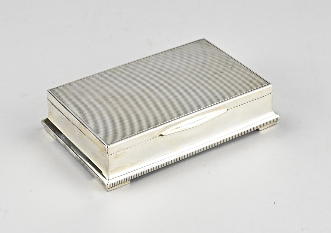 Silver lid box: Silver lidded box, 835/000, with a wooden interior. Rectangular box with a hinged lid with a diagonal line decoration. The lower edge with 4 legs is provided with a ribbed finish. approx. 430 grams.