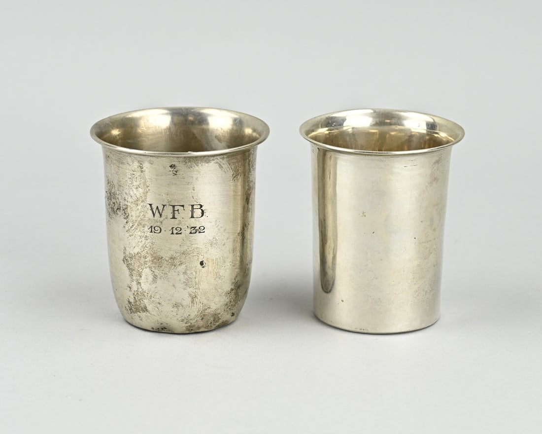 2 Silver birth cups: Two silver birth cups, 833/000, One slightly more rounded model with a folded edge and an engraving: WFB19-12-32. ø 6x7cm. MT.: Begeer, Voorschoten, jl.: T:1929. Somewhat dented along the bottom