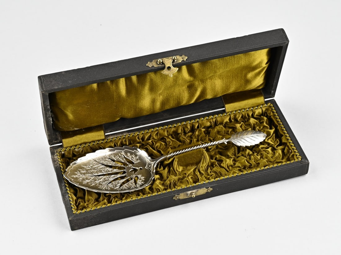 Silver wet fruit scoop in cassette: Silver wet fruit scoop in cassette, 833/000, scoop in the shape of a leaf with serrated decoration, a twisted handle with leaf element. MT.: C.Hooijkaas, The Hague, jl.:i:1893. 21.5 cm. approx. 49