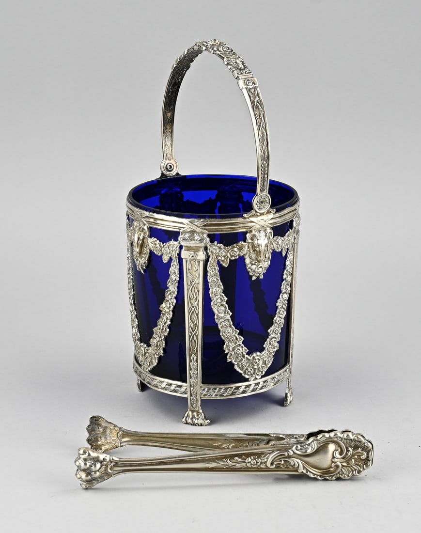 Blue glass sugar bowl in silver frame + sugar tongs: Silver sugar basket with sugar tongs and a blue glass inner container, 835/000. Sugar basket, in Louis XVI style, decorated with garlands, ram heads and placed on 4 claw feet. Importer's mark: C.Bos,