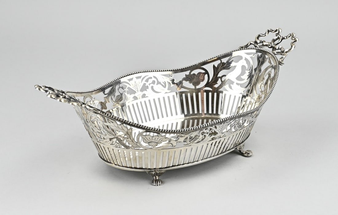 Silver ribbon bread basket: Silver bread basket, 833/00, an oval basket sawn with bars and floral decoration with engraving. Placed on 4 claw feet with 2 handles in the shape of bows. Restoration to one of the bows. MT.: