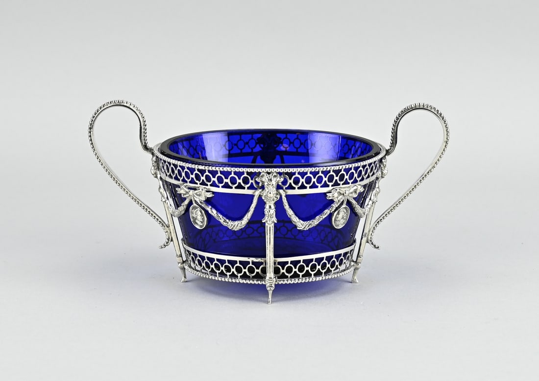 Silver bowl: Sugar bowl with silver holder with blue glass, 833/000, oval sawn silver holder with garlands, bows, medallions and pearl rim. Schoonhoven, jl.:D:1913. Silver approx. 125 grams. In good condition.
