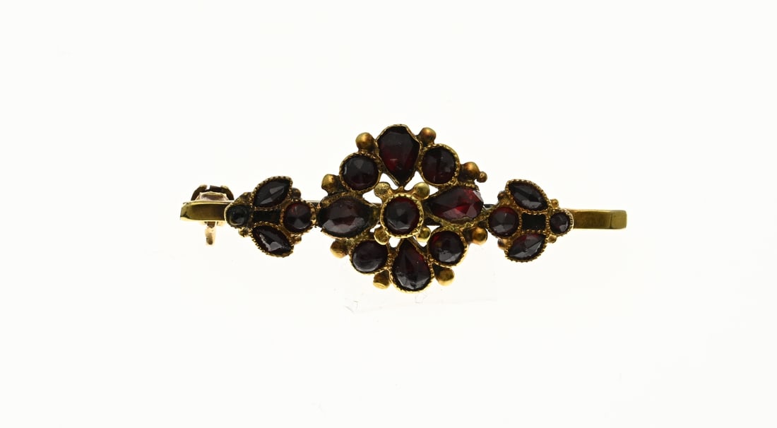 Gold brooch, garnet: Yellow gold brooch, 585/000, with garnet. Bar brooch with soldered elegant gold element with garnets. Base pin. Total approx. 2.9 grams. In good condition.