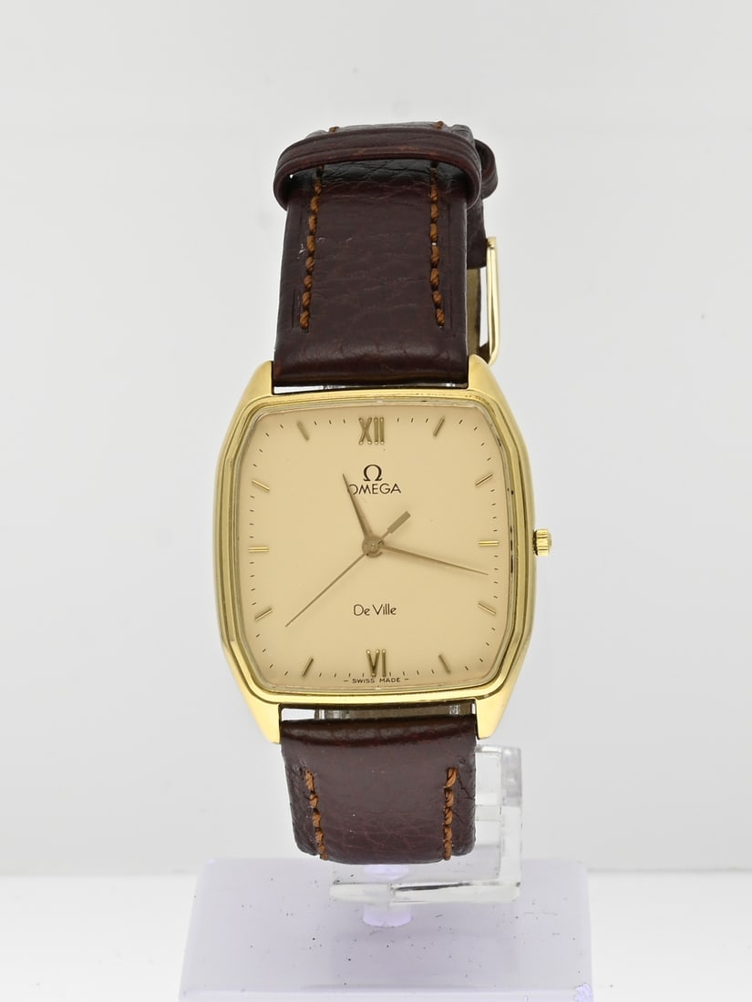 Omega de Ville, quartz: Vintage Omega de Ville watch, with a goldplated rectangular contoured case. Equipped with a yellow dial. Quartz. Working. Attached to a brown leather strap. ref. no.: 1417. Case width 30 mm. In good