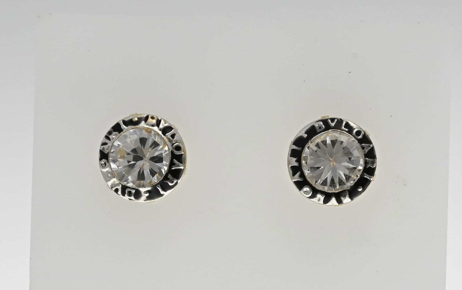 Gold earrings with zirconia: Yellow gold stud earrings, 585/000, with a zirconia and around it a border with text and black inlay. ø 7.5mm. approx. 1.6 grams. In good condition.