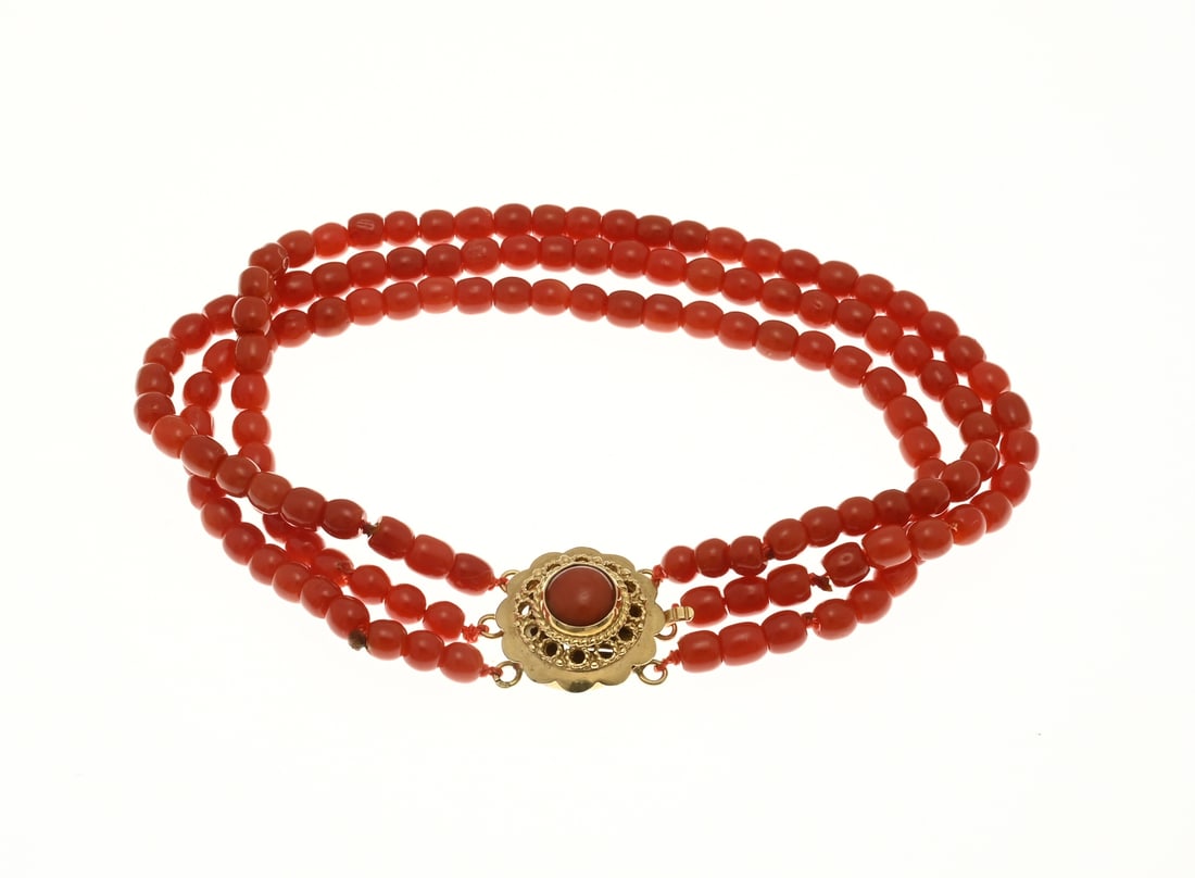 Red coral bracelet with gold clasp: Bracelet of blood coral with yellow gold clasp, 585/000. Bracelet with 3 rows of blood coral, ø 3.8 mm., attached to a round worked yellow gold clasp in flower shape with blood coral. Length 18 cm.
