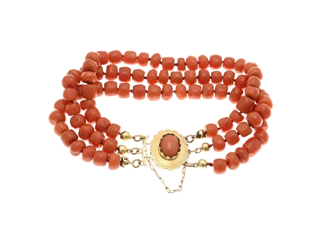 3-Strand red coral bracelet: Bracelet with 3 rows of blood corals, cheese-shaped ø 7 mm., attached to a yellow gold clasp, 585/000, oval model with a scalloped model with engraving and an oval blood coral. With large lacquer