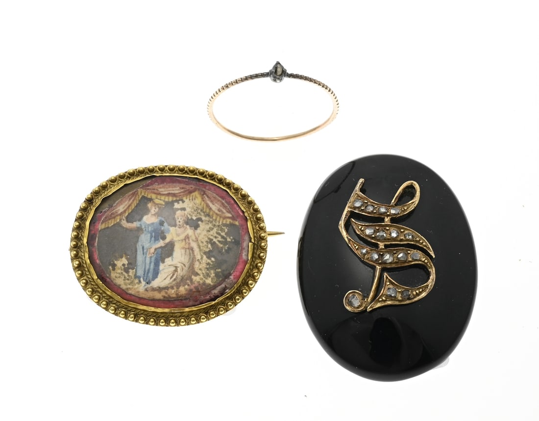 2 Gold brooches and ring: Two brooches and a ring with gold. Fine gold ring with a silver setting with a rough cut diamond, ø 64. A brooch of onyx and a gold element with diamonds, 4x2.7cm. and an oval brooch with gold and a