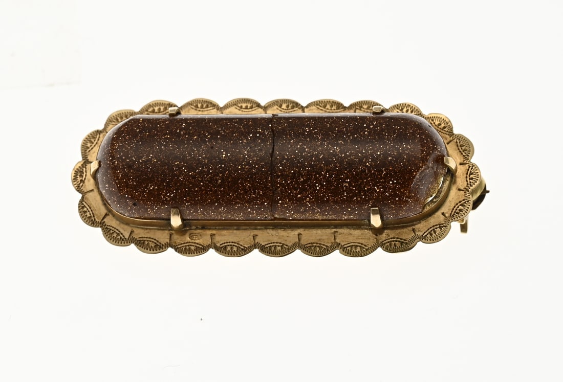 Gold brooch with gold stone: Yellow gold brooch, 585/000, with goldstone. An oval brooch with a scalloped edge with an oval cabochon cut goldstone in the middle with a fracture and chip. 1.5x3.7cm. approx. 5.1 grams. In