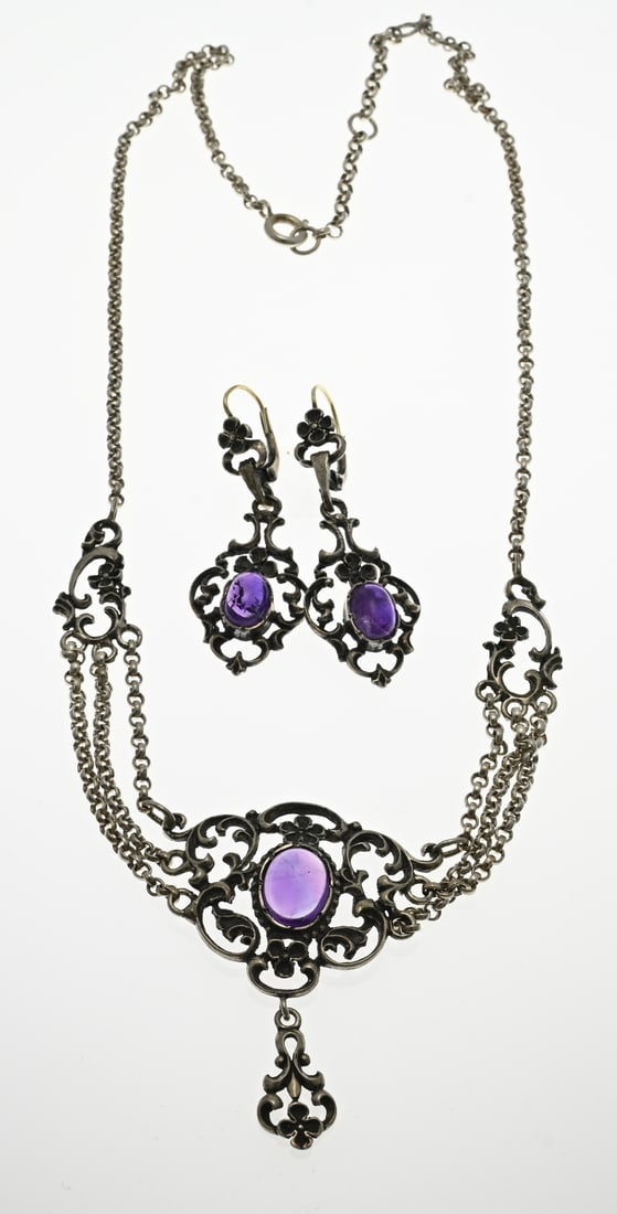 Silver set with purple stone: Silver set with purple stone, with a choker decorated with volutes, flower elements and a purple stone. Length 40-46 cm. And a pair of matching earrings. 4.5 cm. Total approx. 22.7 grams. In good