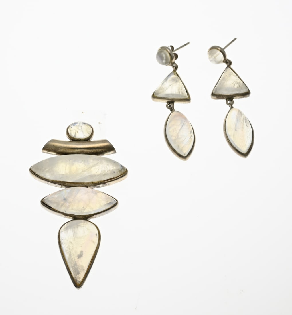 Silver pendant and earrings with moonstone: Silver pendant and stud earrings, 925/000, with moonstone. Pendant with a tubular eye, set with 4 cabochon cut moonstones. 3-6cm. And a pair of stud earrings with a round, triangular and a marquise-sh