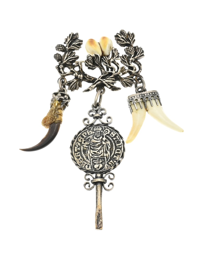 Silver brooch with hunting trophy: Silver brooch, 835/000, with hunting trophy. Floral shaped brooch with teeth and 3 pendants with teeth, nail and a key. 3.5x8.5 cm. approx. 19.3 grams. In good condition.