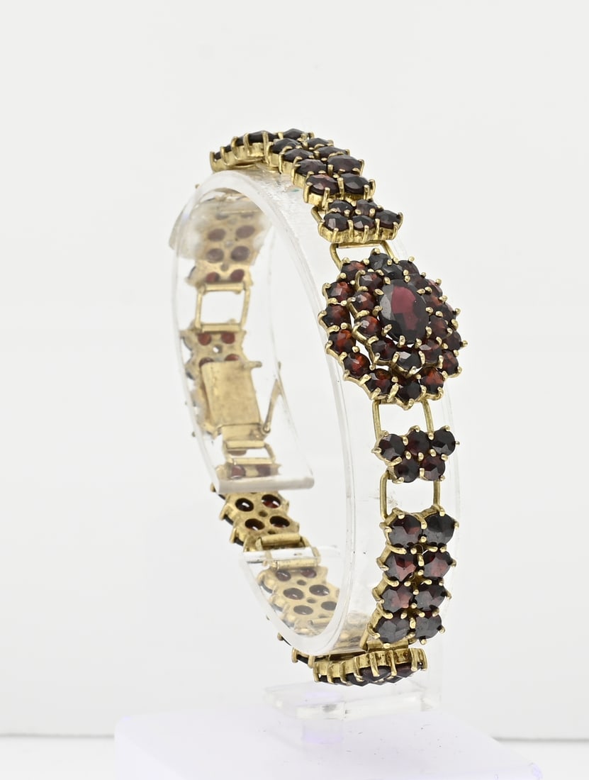 Bracelet with garnet: Double bracelet with garnet. Bracelet with an oval rosette with garnet stones in the middle. The rest of the band consists of 2 rows of garnet stones. Length 18 cm. Width 17 mm. Equipped with a box