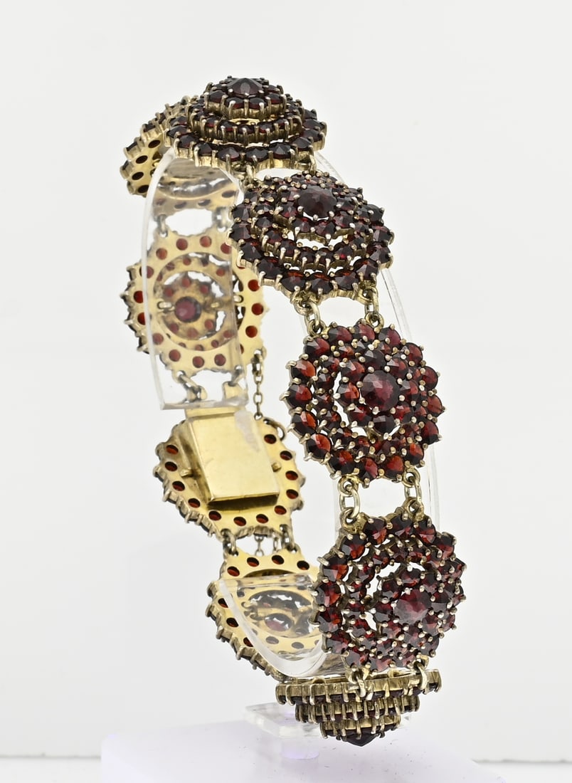 Bracelet with links with garnet: Wide bracelet, silver plated, 835/000, with garnet. Bracelet with 9 links in the shape of a double rosette with geranite stones. With box clasp and safety. Width 21 mm. Length 20 cm. approx. 40.9