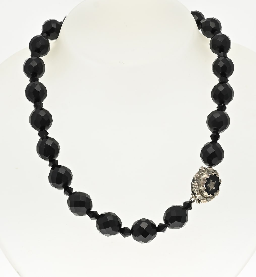 Necklace of jet and silver: Necklace of faceted jets, ø 12 mm., attached to a silver round clasp with onyx and star. approx. 57.5 grams. Length 42 cm. In good condition.