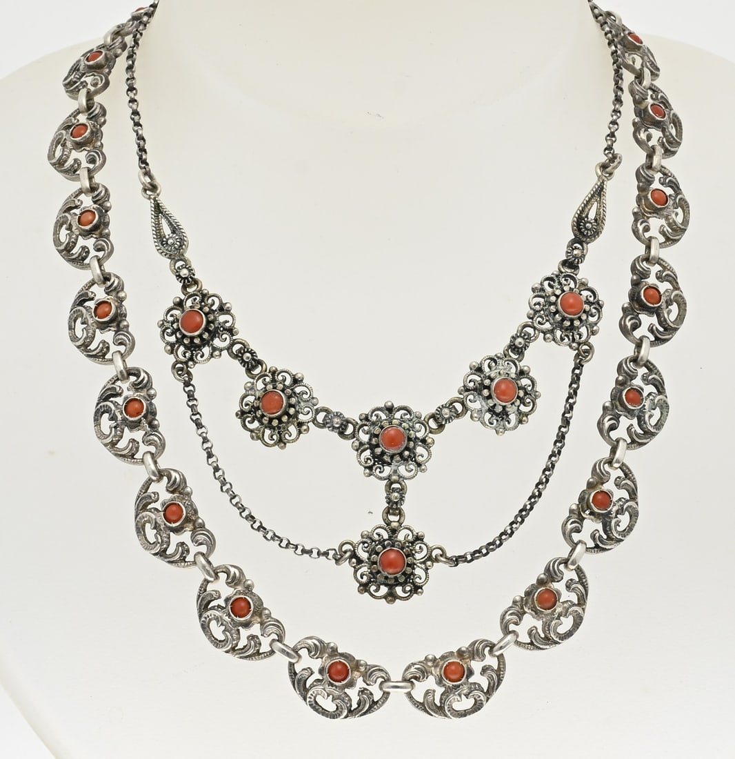 2 Silver chokers with blood coral: Two silver chokers with blood corals. A necklace with anchor link with a silver element in the middle with 6 flower elements with blood coral. And a choker with oval contoured links with volutes and