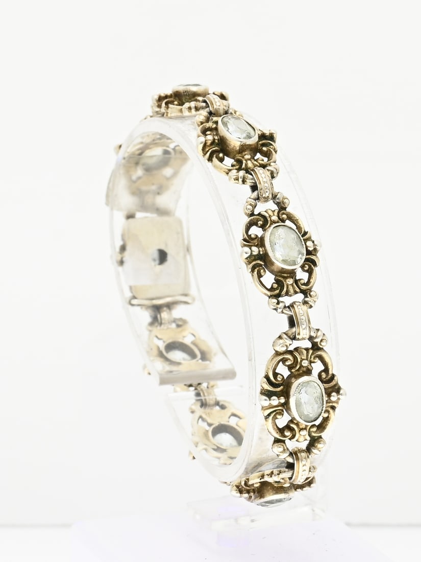 Silver bracelet with blue stone: Silver bracelet, 925/000, with blue stone. Bracelet with oval floral shaped links with volutes, with an oval faceted blue stone in the middle. Fitted with a box clasp. 18 cm. Width 12.5 mm. approx. 18