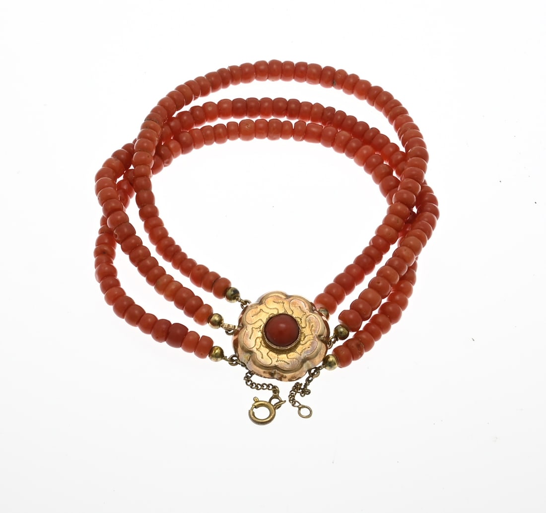 Blood coral bracelet: Bracelet of 3 rows with blood corals, ø5 mm., cheese-shaped, attached to a round yellow gold clasp, in flower shape with blood coral and engraving. approx. 23.9 grams. length 21 cm. The bracelet is