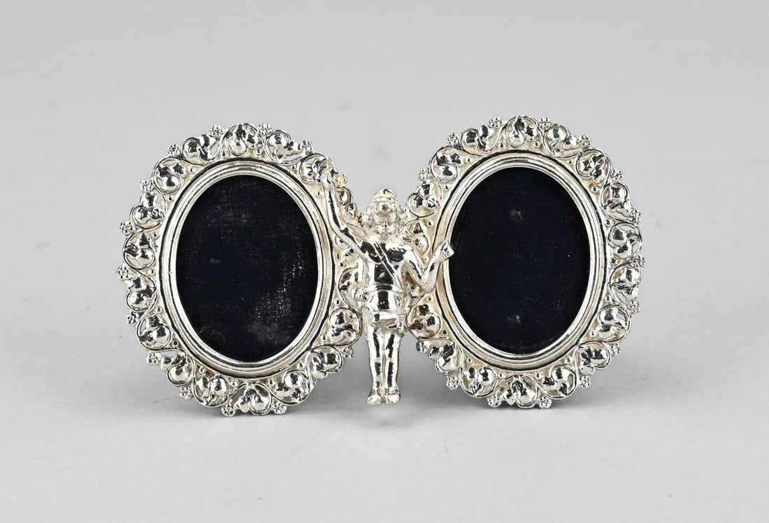 Double silver photo frame: Double photo frame with silver, 800/000. Frame with 2 oval silver frames with curls and volutes and a girl figure in the middle. With black holder. Total approx. 103 grams. 12x7cm. n good condition.