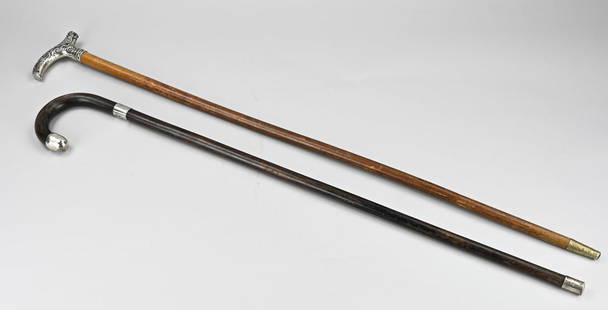 2 Walking sticks with silver work: Two walking sticks with silver, 800/000, a walking stick with a wooden stick and a grip, richly decorated with volutes and acanthus leaf. And one with a curled grip with 2 silver elements. 81-90 cm. I