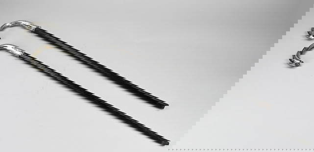 2 Walking sticks with silver work: Two walking sticks with silver, 800/000, Wooden walking sticks with a curled silver grip decorated with floral work. 83-84cm. Minimal dents. In good condition.