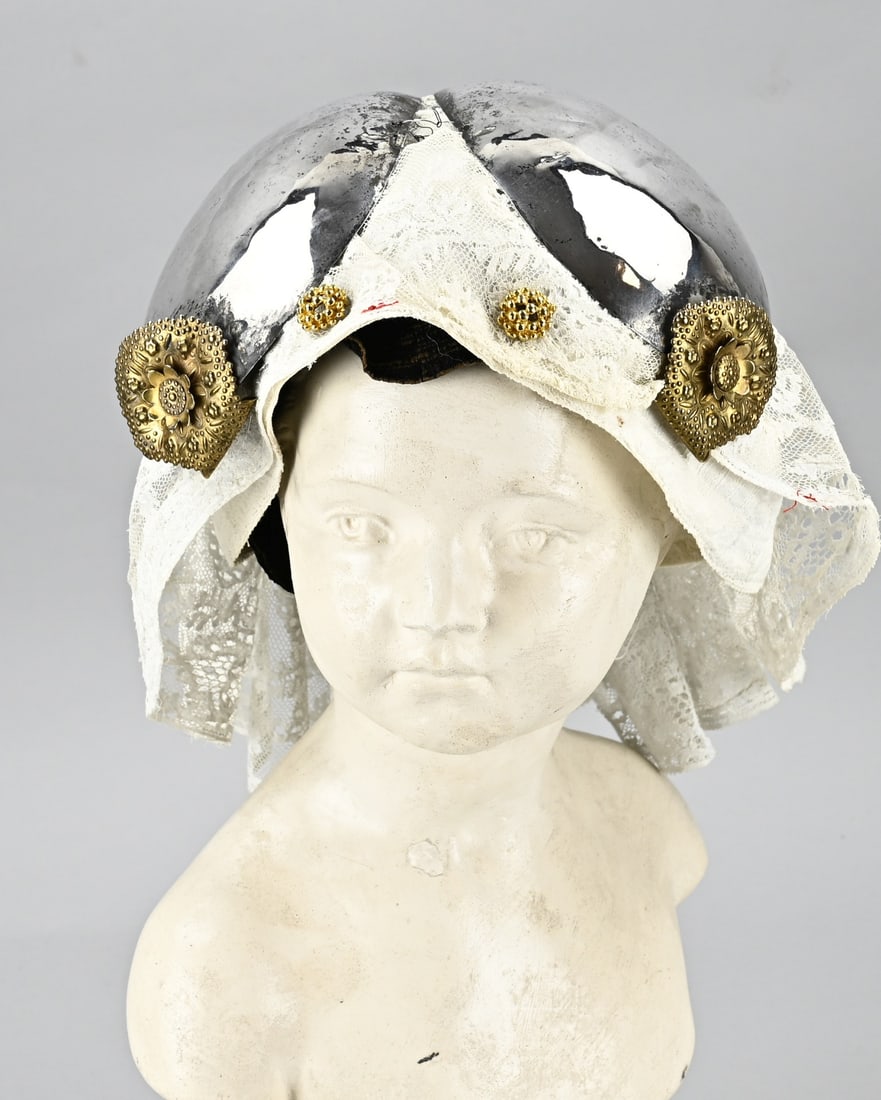 Silver cap, gilded parts: Silver ear iron, 833/000, provided with double pieces. With a lace cap provided with double pins. Various dents, otherwise in good condition.