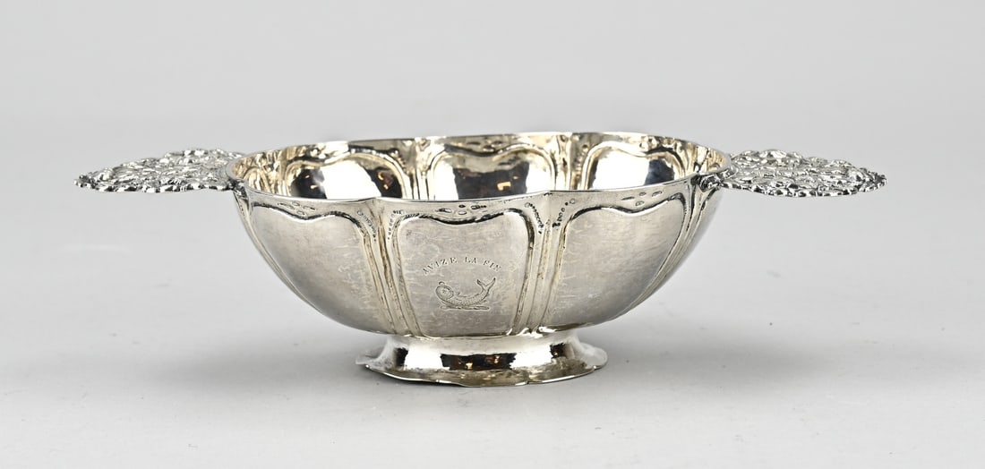 Frisian brandy bowl: Frisian silver brandy bowl, chased oval model, scalloped with heart fillet, on an oval contoured foot. The horizontally placed handles are decorated with floral elements. 23x11.5x6cm. MT.: Arjen