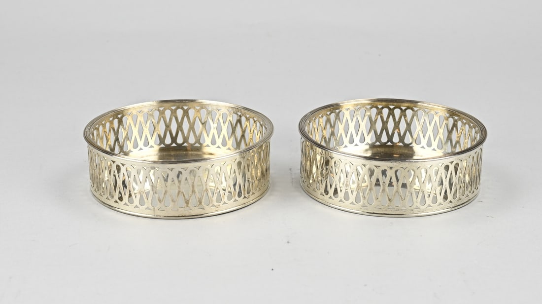 2 Silver bottle racks: Two silver bottle racks, 833/000, sawn model with figure eight work and a rim with fillet work. ø 11.5cx4m. Total approx. 198 grams. MT.:A.Presburg, Haarlem. jl.:E:1939. In good condition.