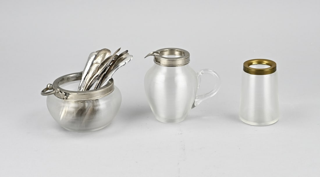 Set of wire glass with silver cutlery: Three parts wire glass with silver cutlery parts. Cream set of wire glass with a sugar bowl, milk jug and spoon vase with a metal rim and various silver spoons and forks in it. And 2 plated butter
