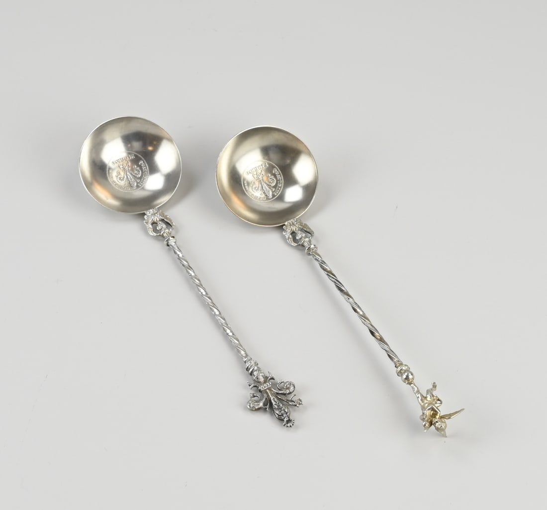2 Silver spoons: Two silver spoons, 800/000, with a round bowl with a print of a coin: Quattrini Cento Fiorino. A start at the bowl with an angel, a twisted handle, one crowned with a gilded angel and one crowned