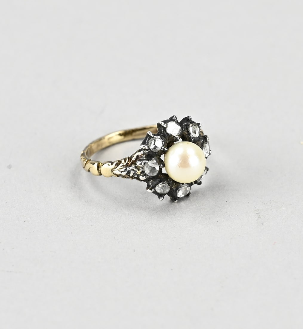 Gold ring with diamond and pearl: Yellow gold ring, 585/000, with pearl and diamond. Ring with a decorated band and a silver rosette in the middle set with a cultured pearl, ø 6.2 mm. Around the pearl is a rim with 8 diamonds with an