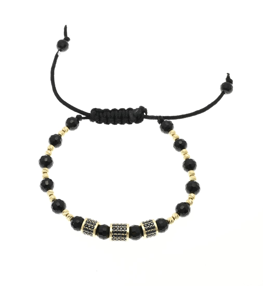 Bracelet with golden balls: Black knotted bracelet with black faceted beads, cut yellow gold balls and 3 gold cylindrical elements set with black zirconia. ø 7 mm. Total approx. 8.9 grams. In good condition.