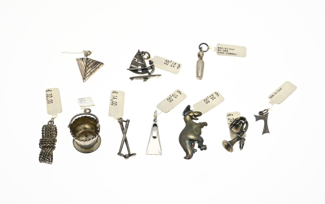 Lot with silver charms, 10x: Lot with 10 silver charms, 925/000, including a dinosaur, surfer, wave, cone, bucket and a flipper. 1.5-3.8mm. Total approx. 25 grams. New