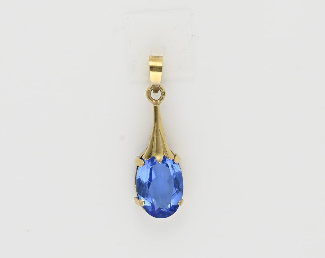 Gold pendant with blue stone: Yellow gold pendant, 585/000, with blue stone. Pendant with an oval faceted blue glass stone. Length 28 mm. including eye. approx. 1.7 grams. In good condition.