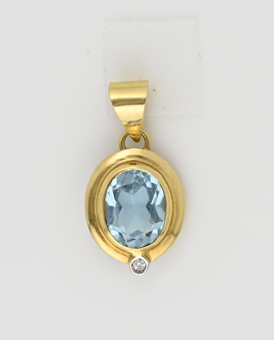 Gold pendant with blue topaz (set): Yellow gold pendant, 750/000, with a blue topaz and diamond. Oval pendant with an oval yellow gold edge, set with an oval faceted blue spinel and decorated at the bottom of the pendant with a