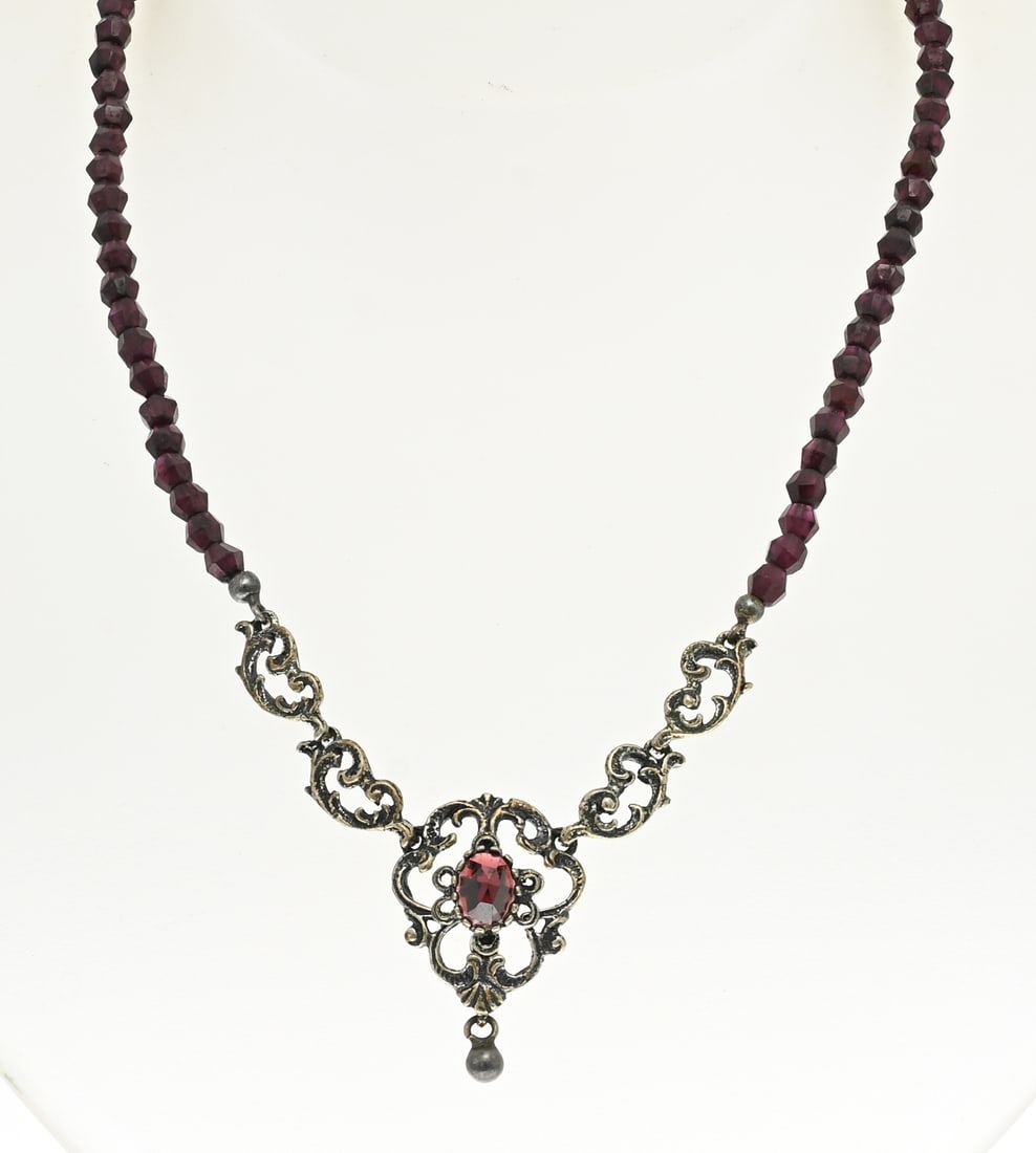 Choker with garnet and silver: Choker with garnet and silver, 835/000. Necklace of garnet stones and in the middle an openwork silver element with volutes and garnet stone. Length 44-49cm. In good condition.