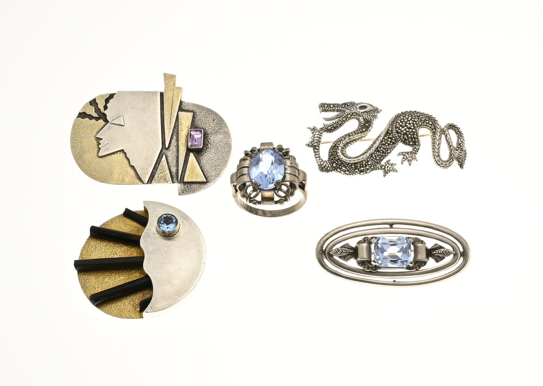 Lot with brooches: Lot with 4 silver brooches and a ring, 925/000, a brooch and ring with blue stone, a dragon with marcasite and 2 designer brooches. Total approx. 51.3 grams. In good condition.