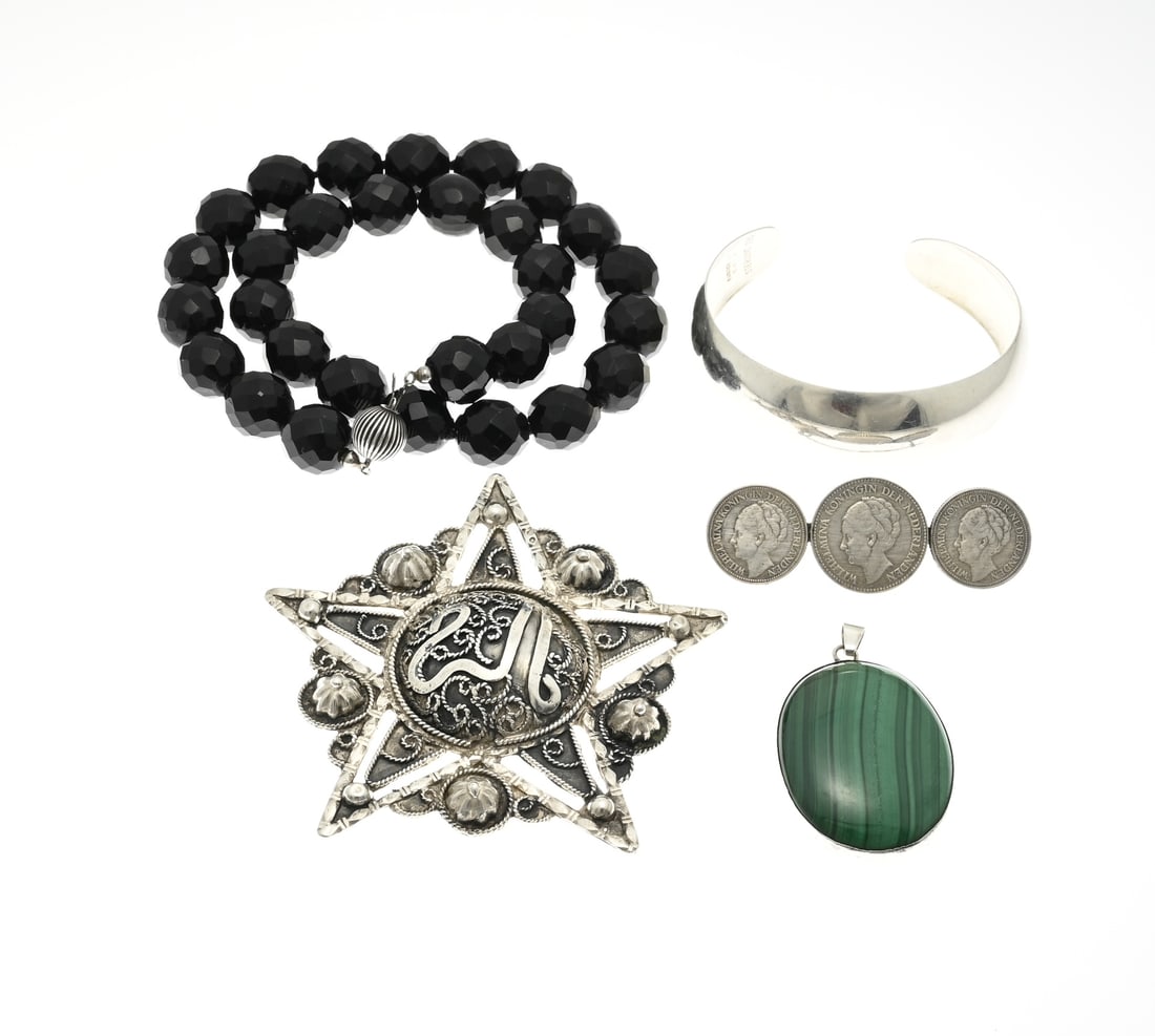 Lot of silver jewelry.: Lot of silver jewelry with a jet necklace with silver clasp, a brooch made of 2 quarters and a guilder, a pendant with malachite, a convex clamp band and a silver star decorated with rosettes and