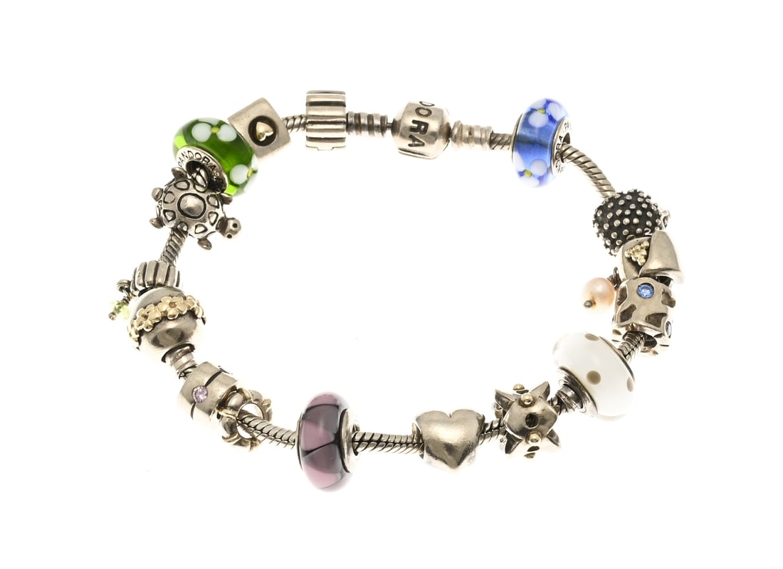 Pandora bracelet with gold charms: Silver Pandora bracelet, 925/000, with 16 charms, 5 of which are gold and 4 of which are Murano glass beads. The bracelet has a Pandora clasp. Length: 21 cm. Approx. 65.7 grams. In good condition.