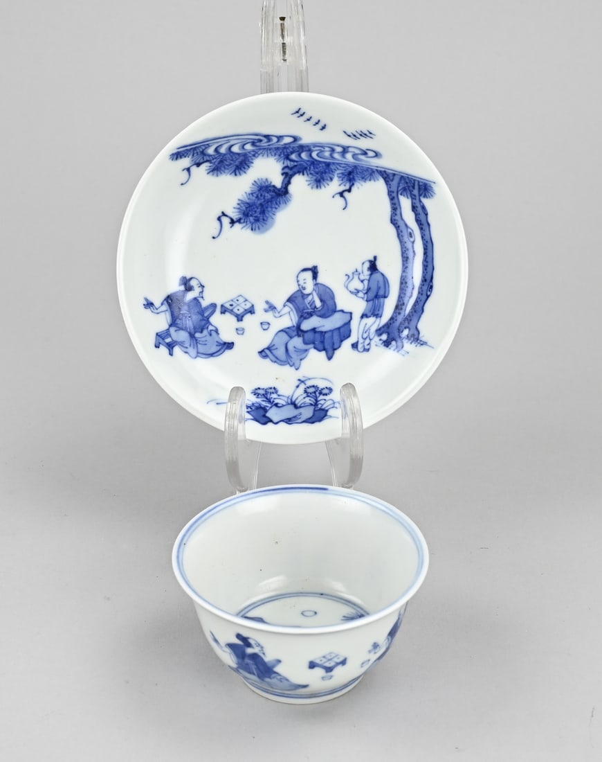 Chinese cup + saucer: Chinese porcelain cup and saucer with figures playing games in a garden setting. Six-character mark on the bottom. Dimensions: 6 x Ø 11 cm. In good condition.