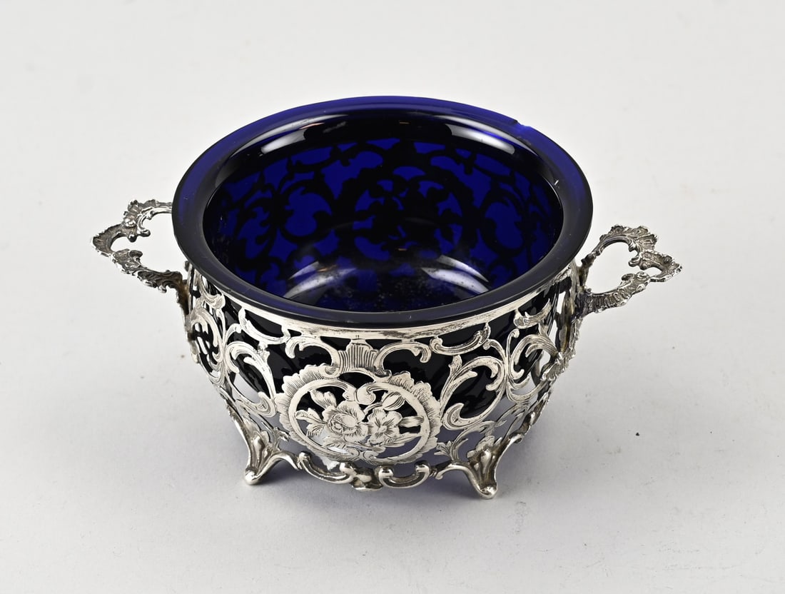 Silver openwork basket: Silver basket, 800/000, with blue glass liner. Round sawn silver holder with volutes, pumpkin, and grid pattern. Decorated with engraving. The basket stands on 4 legs and features 2 vertically placed