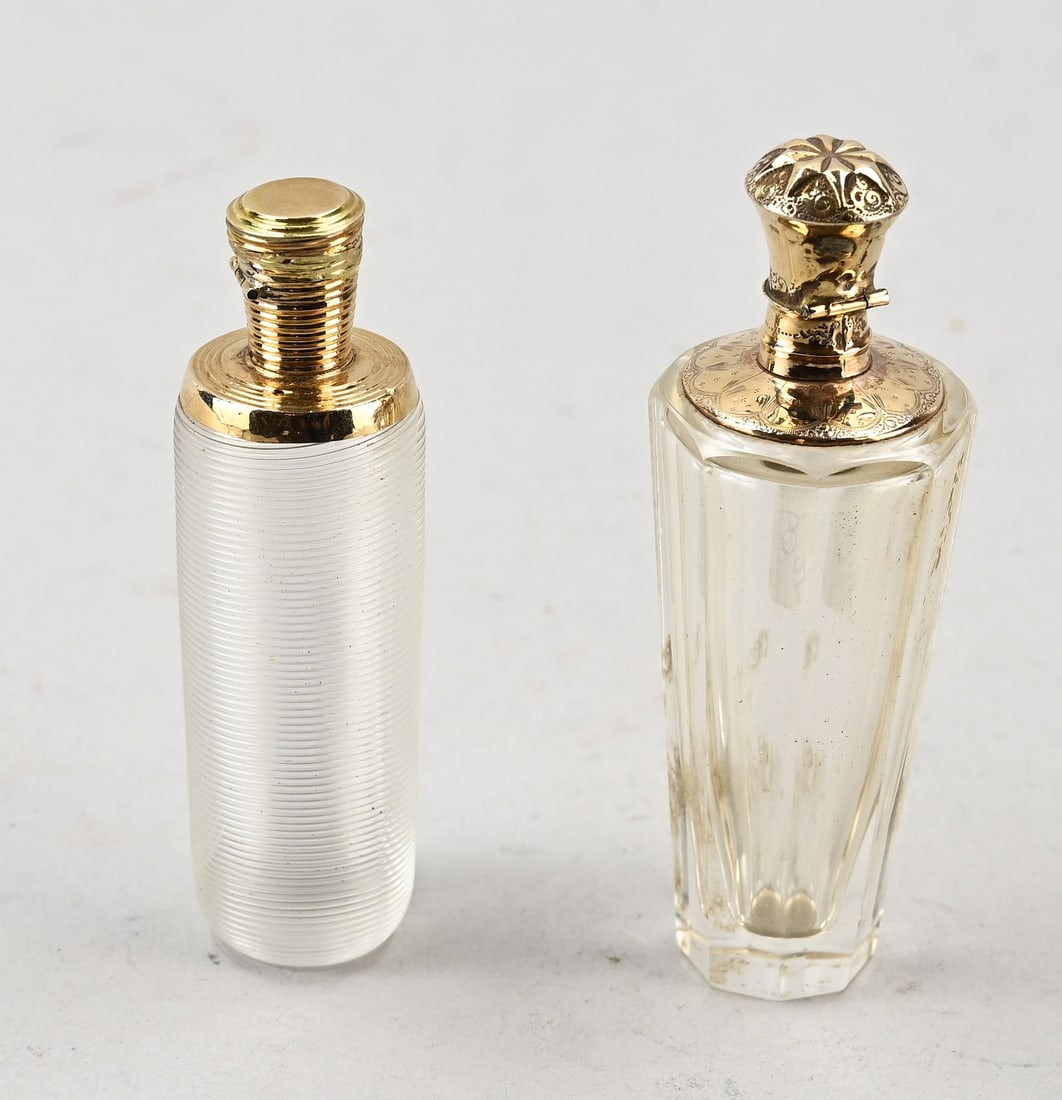 2 perfume bottles with gold: Two perfume bottles with yellow gold collar and cap, 585/000, cylindrical model with wire glass and a wide gold collar and cap with line work. With inner stopper. And a conical bottle with cut work