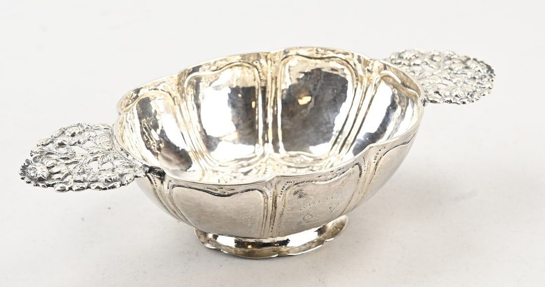 Silver brandy bowl: Frisian silver brandy bowl, chased oval model, scalloped with heart fillet, on an oval contoured foot. The horizontally placed handles are decorated with floral elements. 23x11.5x6cm. MT.: Arjen