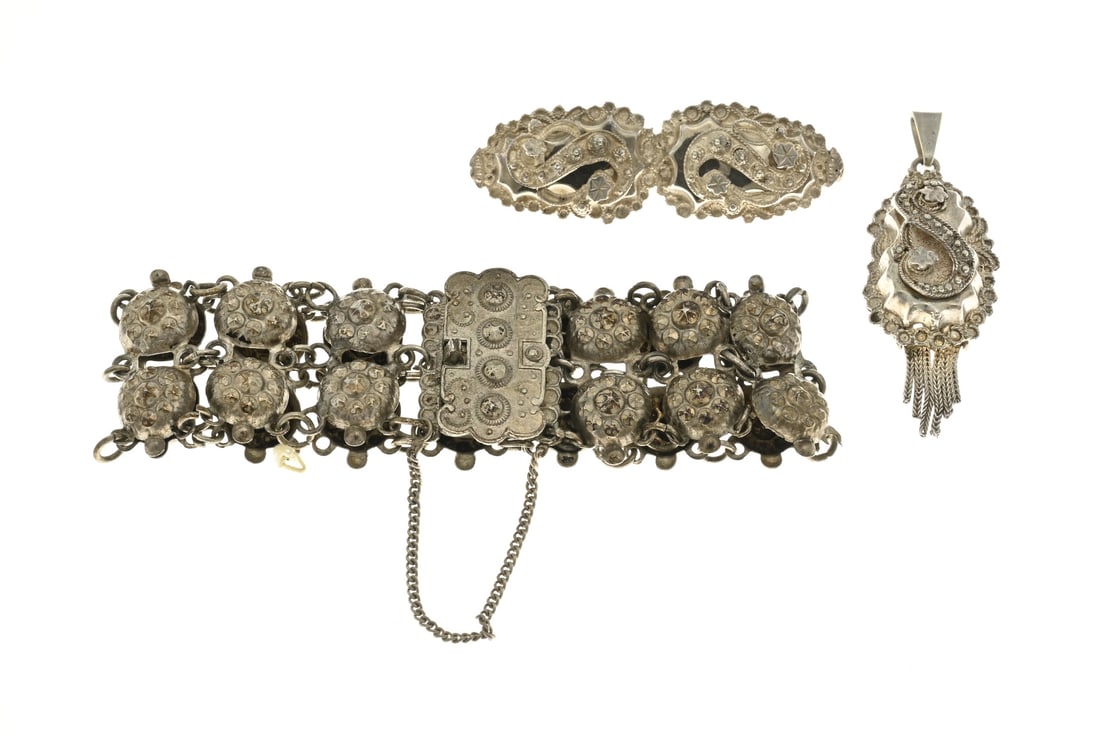 Lot of silver regional jewelry, 3x: Lot of regional silver jewellery, with a bracelet with stamped links, a brooch made of 2 elements with S-appliqués and a matching pendant with a small beard. Total approx. 21.6 grams. In good conditi