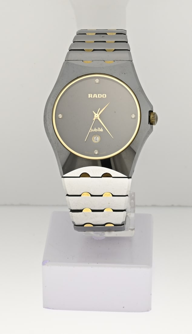 Rado watch: Vintage Rado watch, Jubilee, unisex, grey ceramic with gold detail. Round black dial featuring gold elements and a date display. The strap features gold-colored semi-circular elements. Case width 37